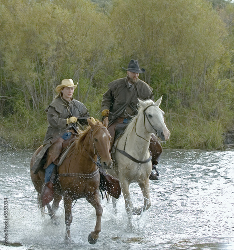 Cowboy,cowgirl galloping across river © outdoorsman