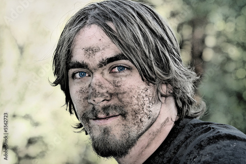 Handsome young man has his face covered with mud 