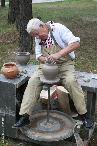 Old potter working with clay on wheel