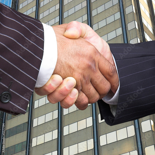 Businessmen in pinstripe suits shake hands.