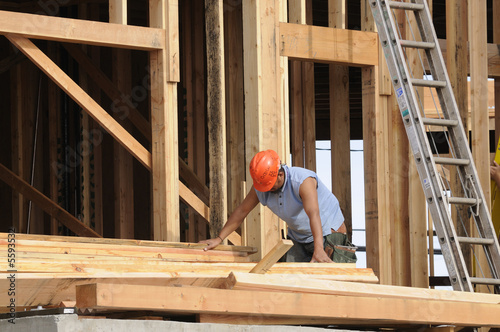 Hispanic Carpenter sorting wood just put in place by a fork lift