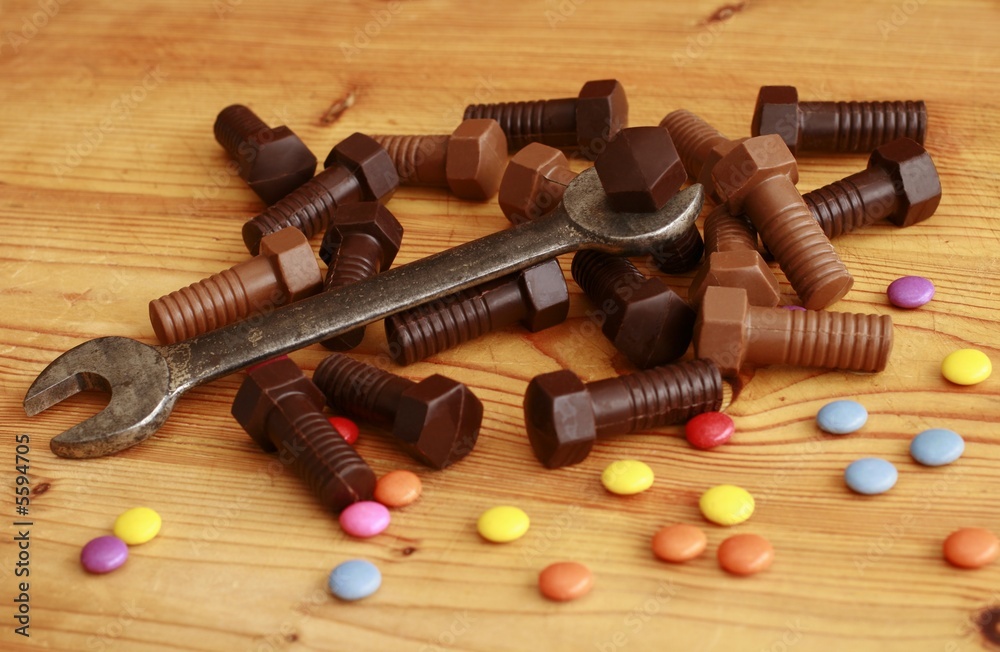 Chocolate screws and old metal spanner on the table Chocolate screws and old metal spanner on the table