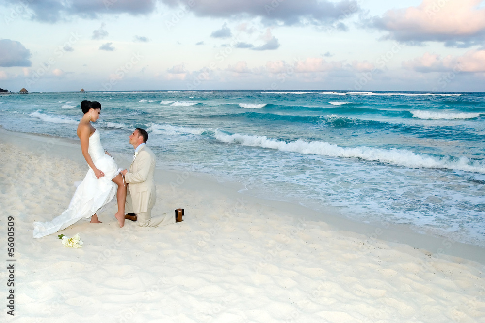 Groom removing the brides garter belt on the beach. Groom removing the brides garter belt on the beach.