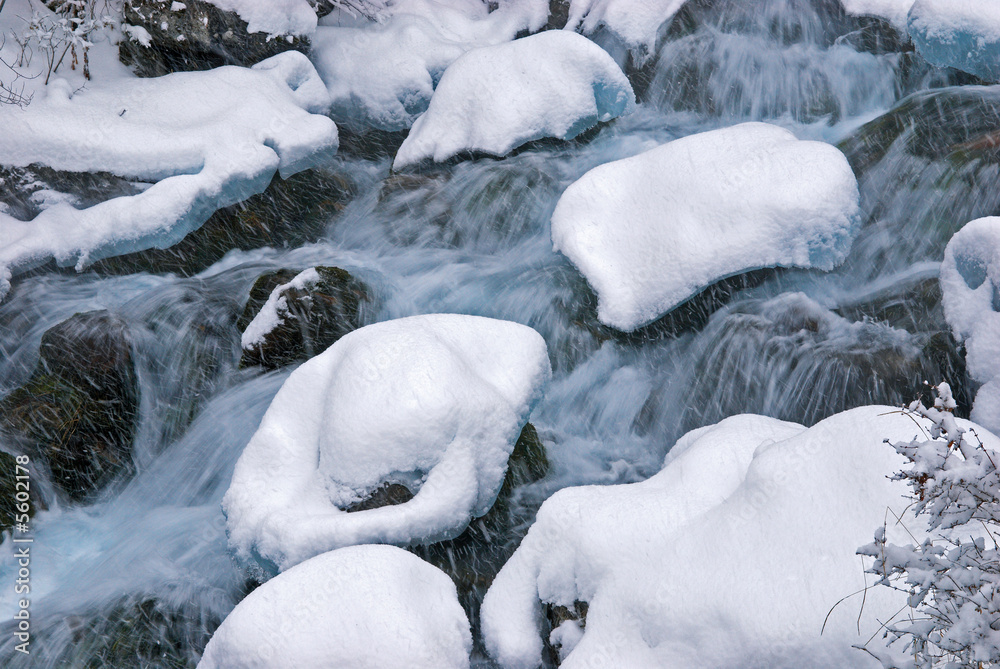 Winter mountain creek cascades during snowfall Winter mountain creek cascades during snowfall