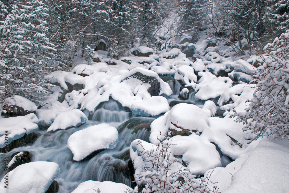 Winter mountain creek during snowfall