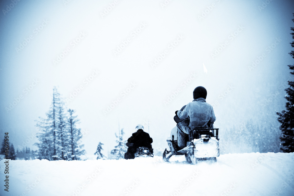 A shot of people riding snowmobile, in blue tone.