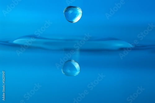 isolated water droplet over blue, with reflection