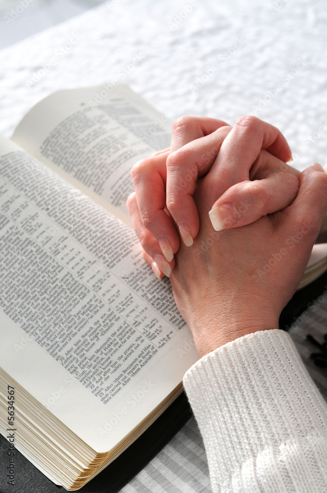 Obraz premium Female hands clasped in prayer ove a Bible