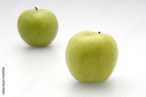 Two fresh green apples lying on a white background
