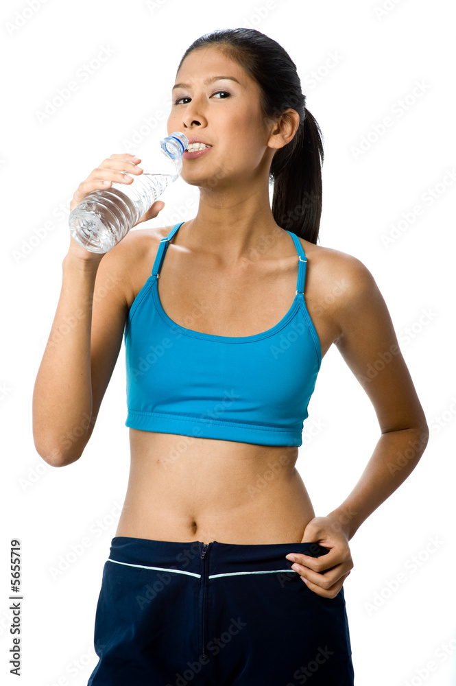 A sporty woman drinking from a water bottle in workout gear A sporty woman drinking from a water bottle in workout gear