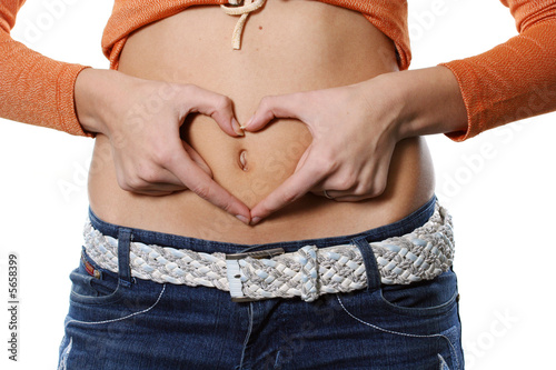 Hands representing heart on a stomach of the girl