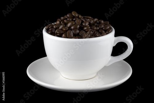 White cup filled with coffee beans on saucer 