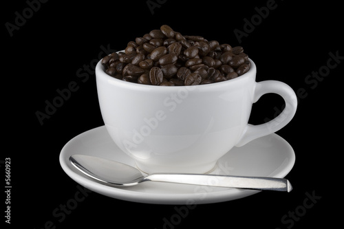 White cup filled with coffee beans on saucer with spoon