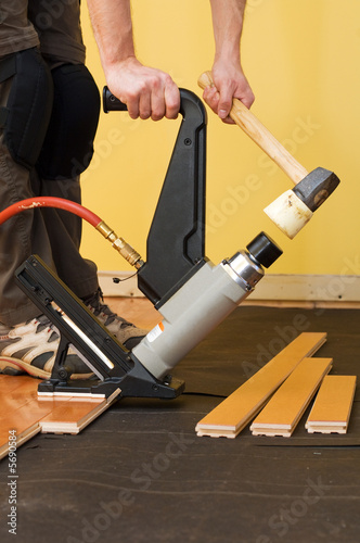 Man installing tongue and groove hardwood floor. photo