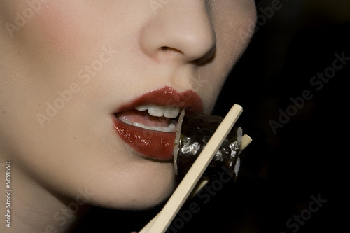 Woman eating sushi with chopsticks.