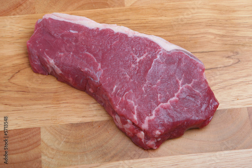 Piece of raw sirloin steak on a wooden chopping board