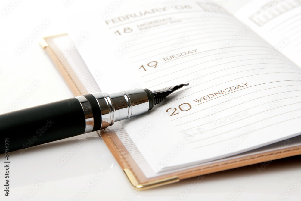ink pen and brown calendar over white background ink pen and brown calendar over white background