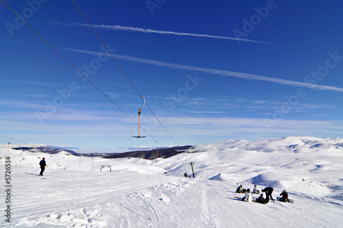 snowboarders near skilift in winter ski resort blue sky