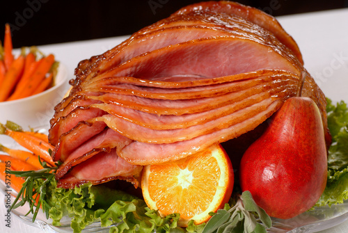 A spiral cut honey glazed Easter ham with fruit and carrots