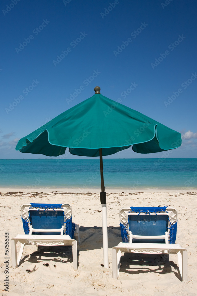 green sun umbrella and two loungers on tropical beach