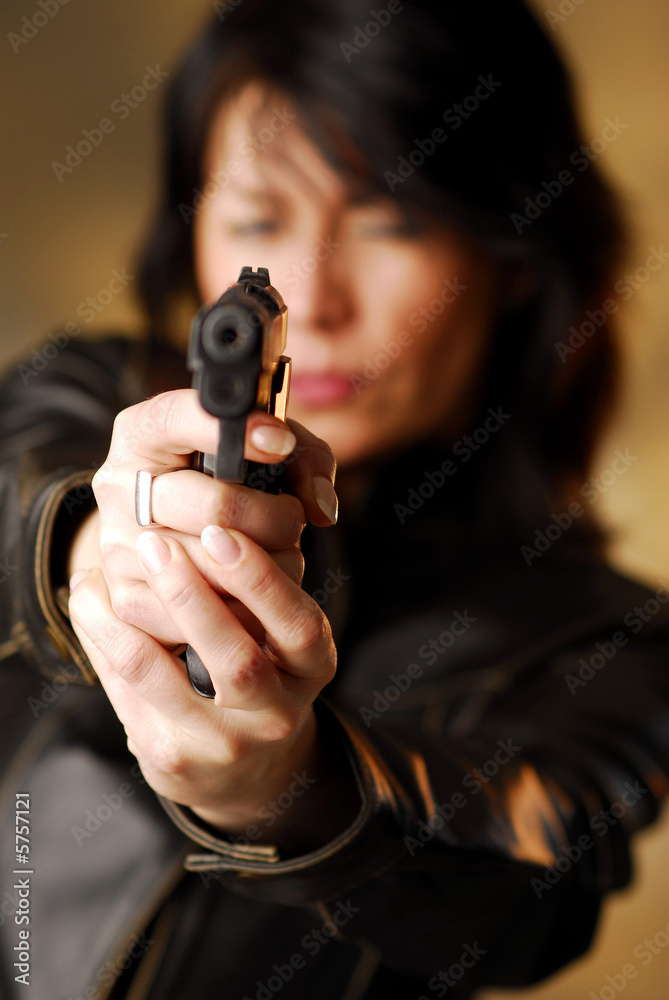 A dark hair woman firing from her gun A dark hair woman firing from her gun