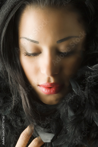 portrait of young cute brunette with black feather around face