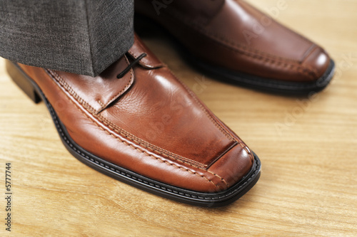 Feet with new brown leather shoes. Very short depth-of-field.