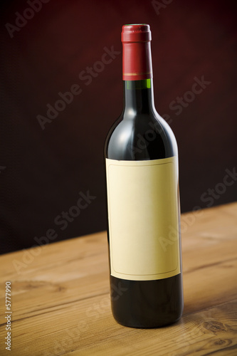 Red wine bottle on wooden table over dark red background