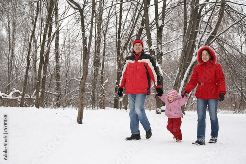 father and mother walk in park with child at winter