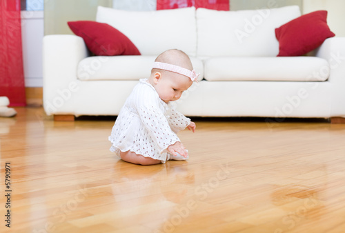 Happy baby girl tuching a hardwood floor