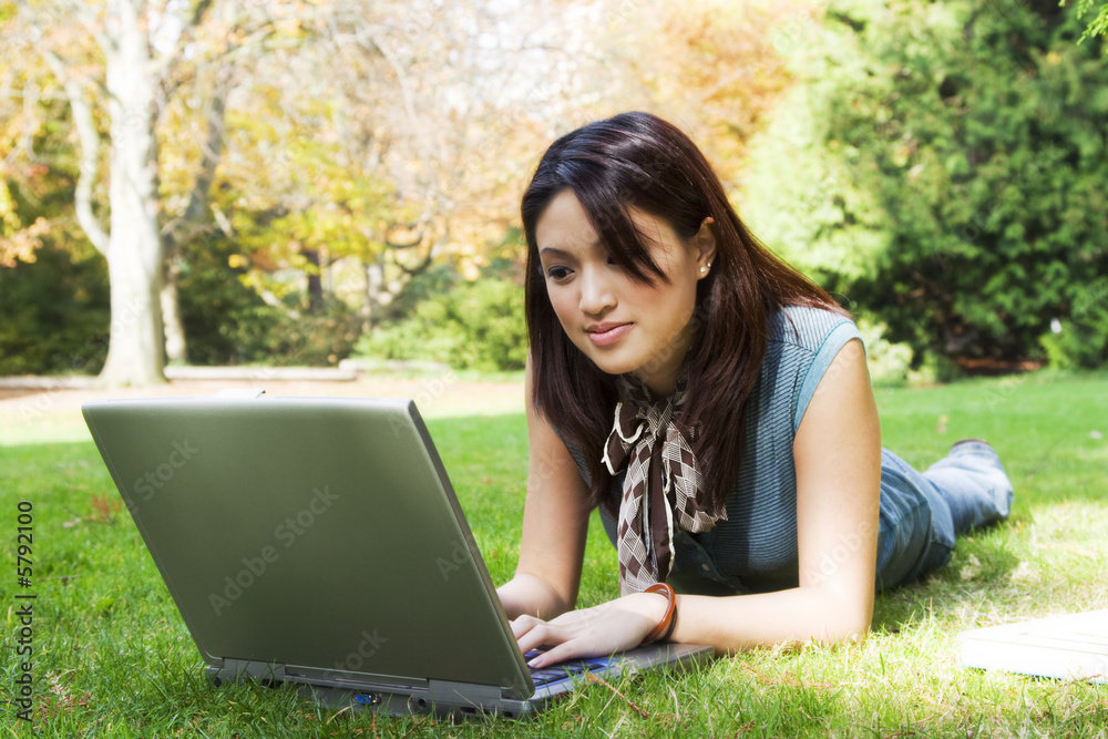 A beautiful college student working on her laptop on campus A beautiful college student working on her laptop on campus
