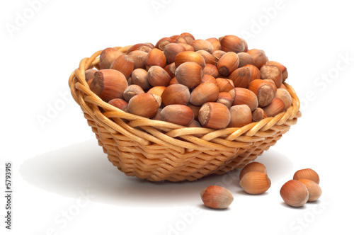 Hazelnuts in a woven basket. Isolated on white. 