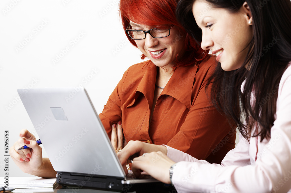 two beautiful women are working at laptop
