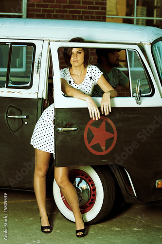 Young Woman standing in alley next to old van.