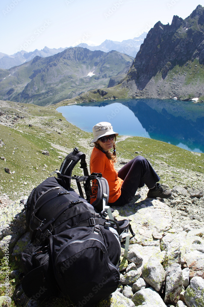 girl hiker on a rest looking at big mountain lake.
