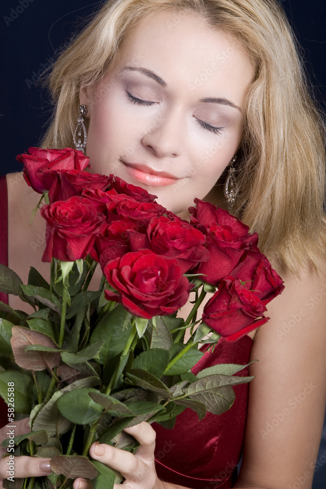 Beautiful blond woman hugging red roses and smelling them Beautiful blond woman hugging red roses and smelling them