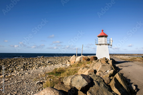 A small lighthouse on a rocky point photo