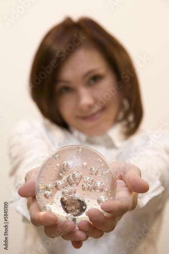 Young woman holds a glasses ball in her hands   