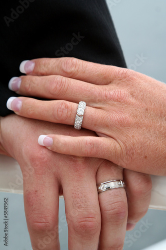 Left hands posed to display wedding rings.