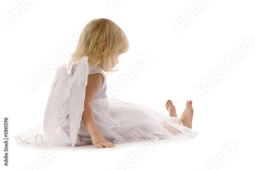 little girl sadly sitting in white dress and angel wings photo