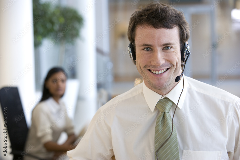 © carlosseller - Businessman with headset and a woman colleague behind © carlosseller - Businessman with headset and a woman colleague behind