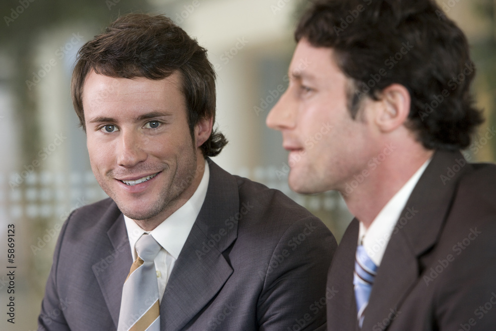 Young businessman with colleague seated next to him Young businessman with colleague seated next to him
