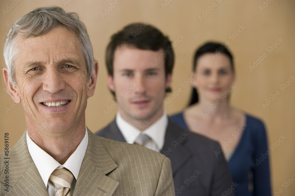 Mature business executive with team behind him Mature business executive with team behind him