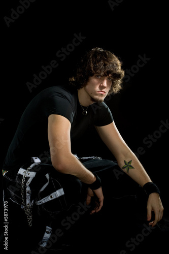 An alternative styled young man posing over black.
