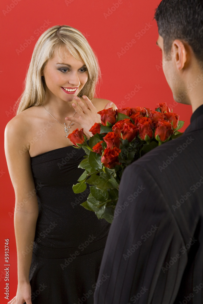 Young man in suit is giving flowers to  woman