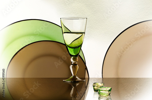 A glass beside a stack of white plates - on white background