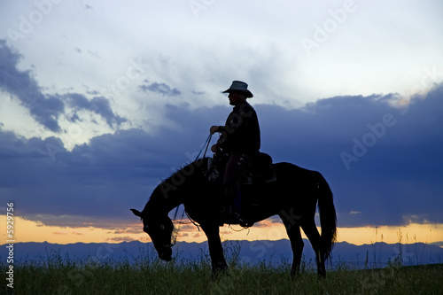 Cowboy silhouetted against a dawn sky. Horse ranch in Montana
