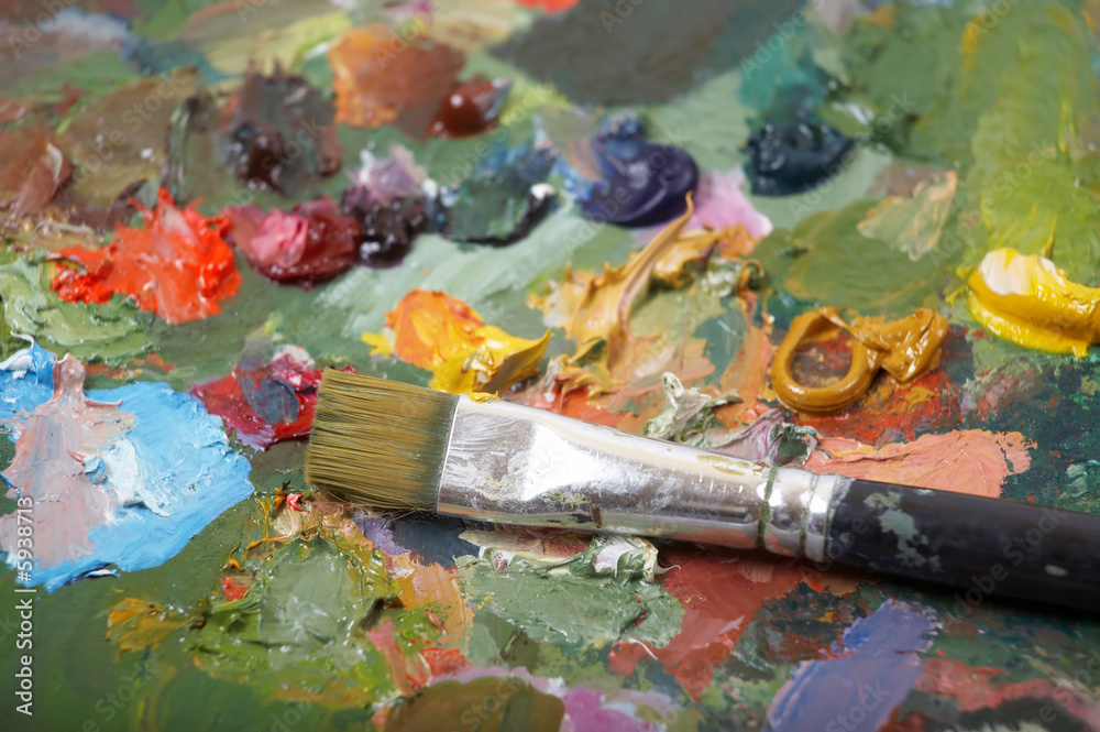 Paintbrush on colorful painting palette. Shallow DOF.. Paintbrush on colorful painting palette. Shallow DOF..
