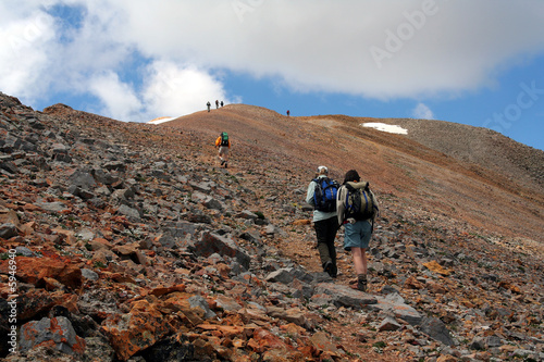 Hikers climbing rocky trail above timberline