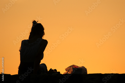 Silhouetted lonely girl looking at sunset
